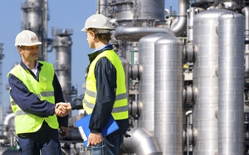 Two workers standing outside of a refinery